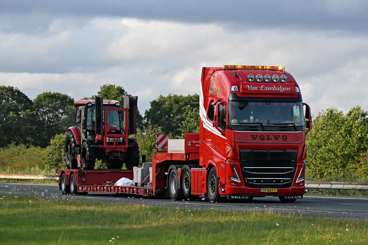 Rode truck met een tractor op een dieplader op de snelweg