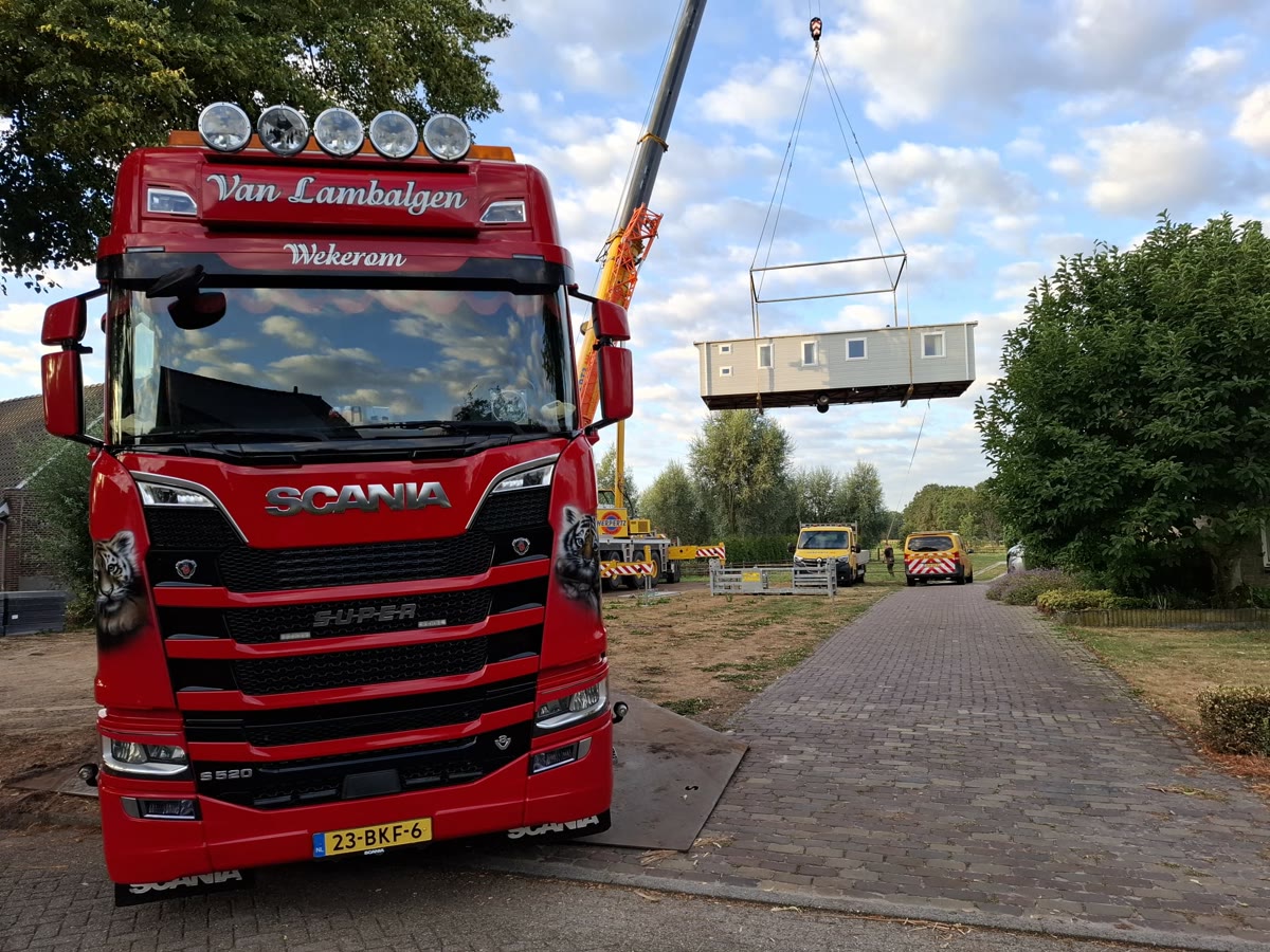 Kraan hijst een unit boven de straat