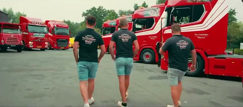 Drie medewerkers van Van Lambalgen lopen langs de rode trucks