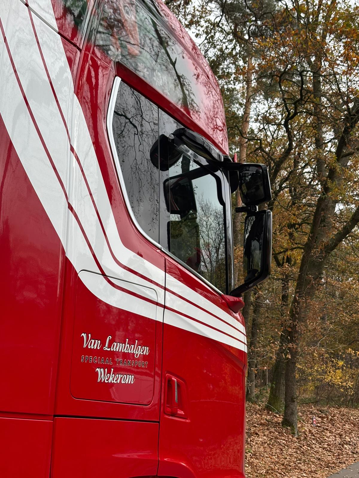 Zijkant van een rode cabine met witte strepen en de naam Van Lambalgen